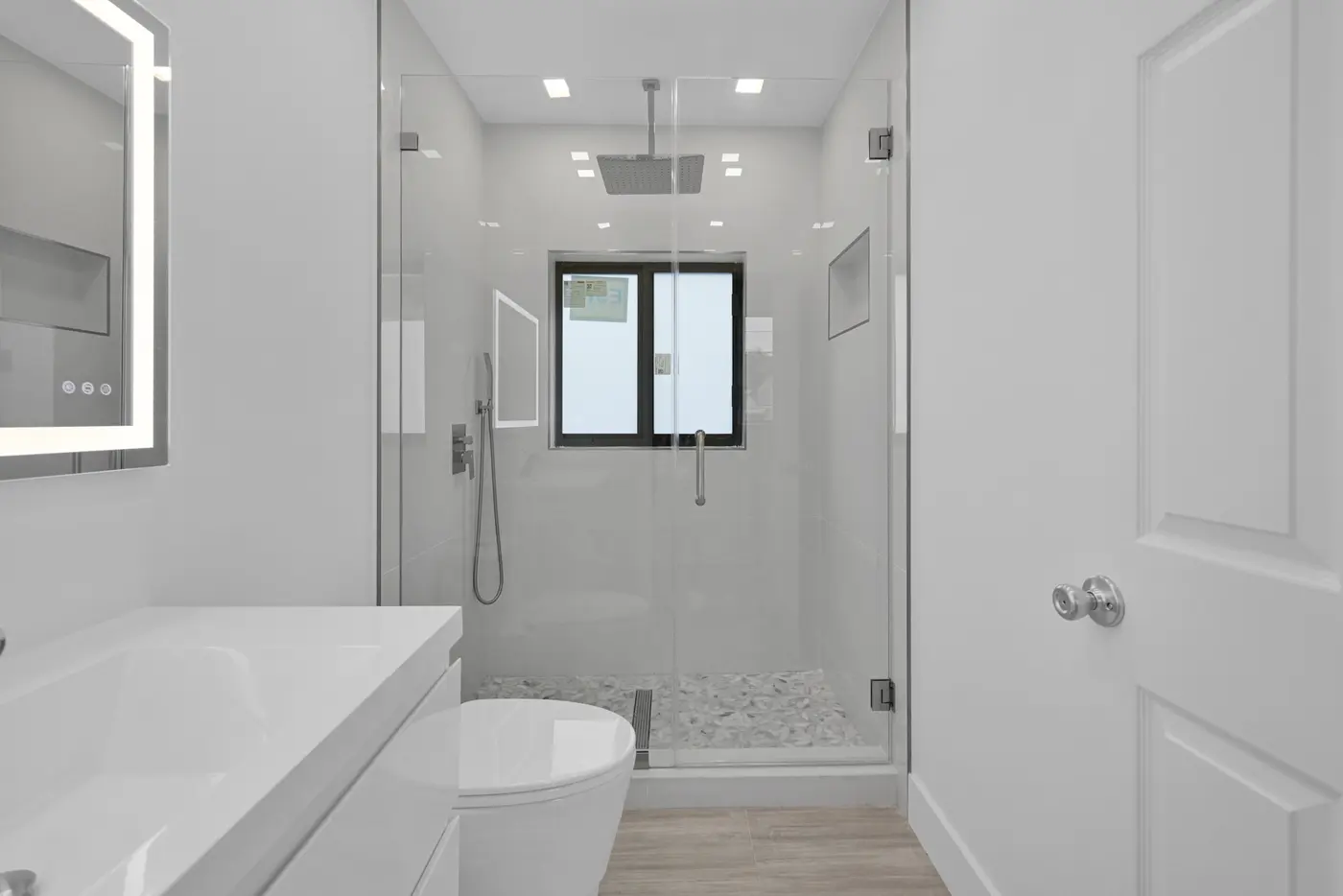 Modern bathroom renovation with a glass shower and light tile